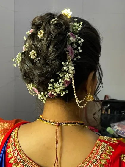 A detailed view of the bridal bun, intricately woven and decorated with fresh flowers and pearl accessories.