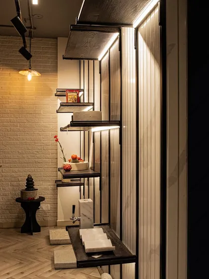 This image captures the layering of light and texture. Track lighting on the ceiling provides focused illumination, while warm pendant lights and integrated shelf lighting create a multi-layered and ambient effect in the space.