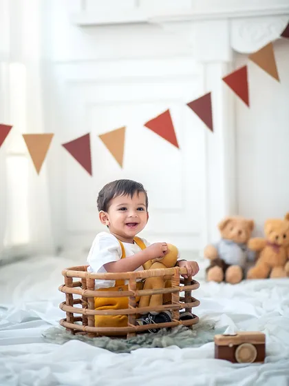 A happy little boy in a basket, surrounded by teddy bears. This is a classic and timeless setup for a sitter or first birthday session.