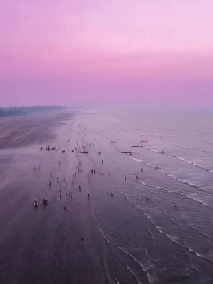 An aerial view of a beach, edited with a strong magenta tint to create a surreal, Mars-like landscape.