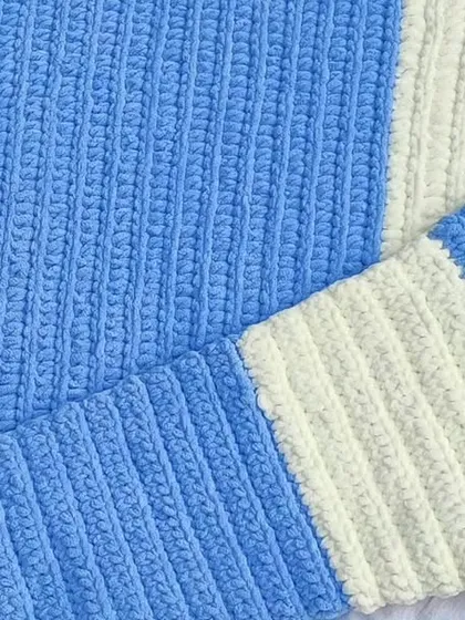 The finished baby blanket folded, highlighting the clean lines of the striped pattern.