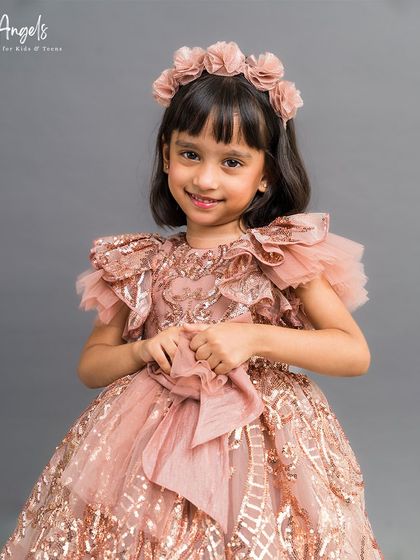 This sequined rose gold gown is pure glamour, with ruffled sleeves and a full, sparkling skirt.