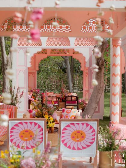 A view through a floral curtain at the 'Gulbahar' courtyard. The design featured intricate walls, painted arches, and quirky, smiling sun prints to kickstart the wedding celebrations.