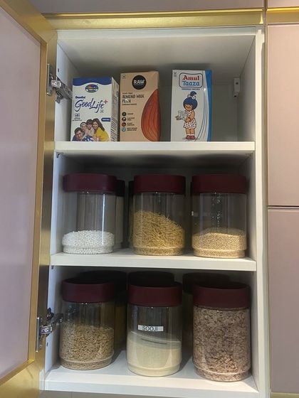 This cabinet combines storage for packaged goods on the top shelf with decanted staples below. This practical approach ensures that everything, from milk cartons to rice, has a designated spot.