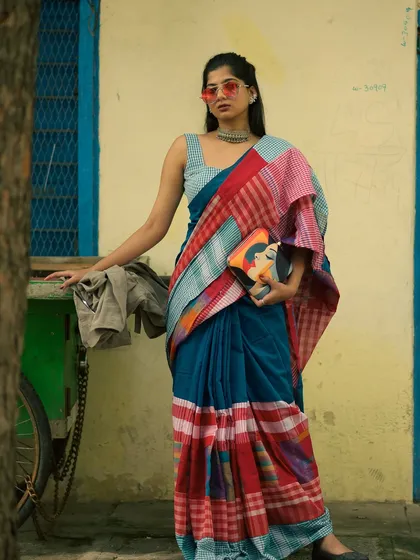 Bringing a modern, edgy vibe to traditional wear. This look pairs a multi-patterned cotton saree with bold sunglasses and a contemporary clutch, showing how ethnic fashion can be styled for a confident, urban aesthetic.
