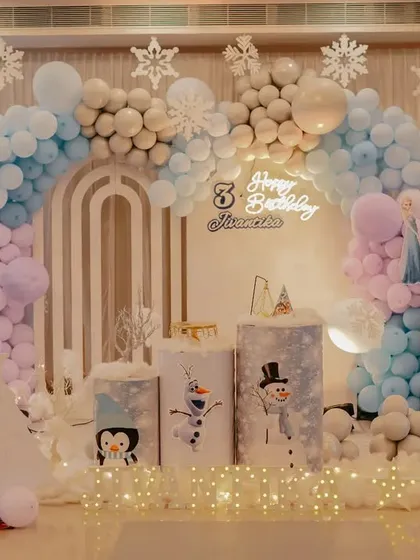 A winter wonderland theme perfect for any Frozen fan. This elegant setup uses a palette of white, blue, and pastel purple balloons, snowflake cutouts, and soft floor lighting to create a magical, snowy atmosphere.