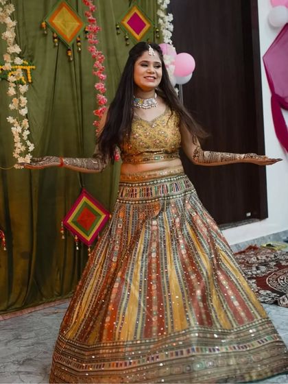 A happy bride-to-be twirling in a multi-color striped lehenga for her Mehendi ceremony. The vibrant colors and playful design are perfect for the occasion.