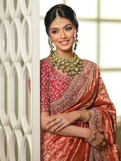 The complete look is one of timeless grace. The saree is draped to perfection, complementing the bride's smile and elegant jewelry.