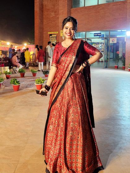 A full-length view of a gorgeous red and black printed lehenga, perfect for a night of Garba. The outfit allows for movement while looking absolutely elegant.