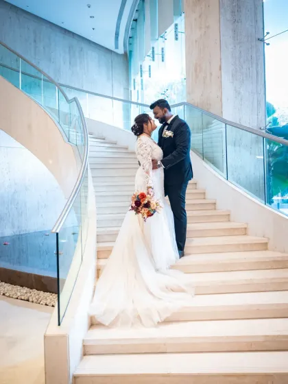 A grand and elegant wedding portrait on a beautiful staircase. The bride's long train looks stunning in this modern and sophisticated setting.