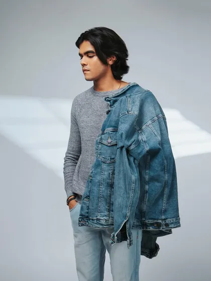 A relaxed pose with the jacket slung over the shoulder. This gives a cool, effortless vibe.