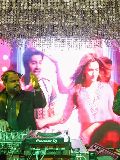 A snapshot from a vibrant Sangeet night. I'm on the decks alongside a talented percussionist, mixing custom Bollywood tracks while a lively visual plays on the screen behind us. This is how we make wedding celebrations unforgettable.