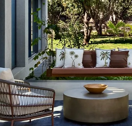 A close-up of the outdoor swing, a perfect spot for enjoying the garden view. The custom cushions with palm tree motifs add a playful touch that connects with the natural setting.