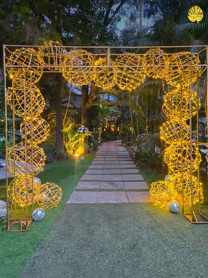A stunning archway made of illuminated wicker spheres creates a magical and artistic entrance for an evening event, lighting up the path for your guests.