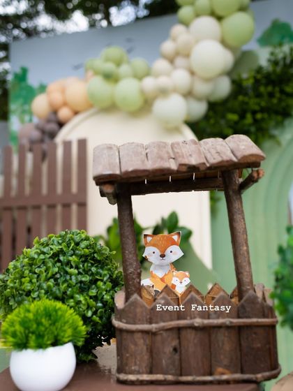 A close-up of a wishing well prop with a tiny fox peeking out, a whimsical detail from Advaith's woodland celebration.