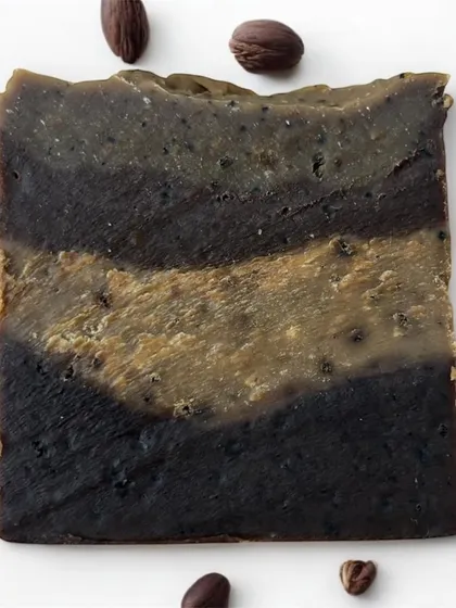 An overhead shot of the textured surface of our Café Latte Soap, surrounded by coffee beans. This bar is a perfect blend of cleansing and moisturizing.