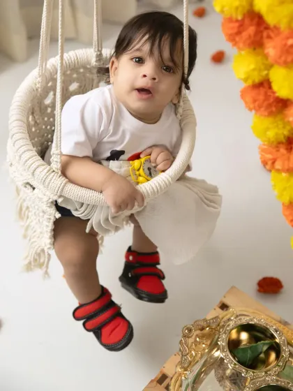 A cute shot of a baby peeking out from behind the marigold garlands during his Raja Parba session.