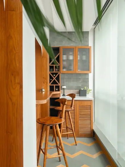We converted a balcony into this cozy bar nook. The space is fully clad in teak wood, with a built-in wine rack and louvered cabinet doors. The chevron-patterned flooring continues from the main living area, creating a seamless transition.