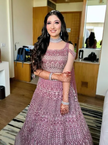 A full-length shot of this princess look. The heavily embellished pink lehenga is the star, supported by glamorous makeup and voluminous curls.