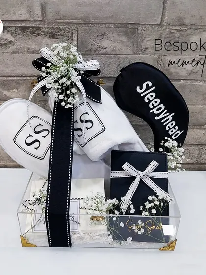 Bespoke mementos for the sleepyhead. This clear acrylic tray is filled with personalized slippers, an eye mask, and other goodies in a chic black and white theme.