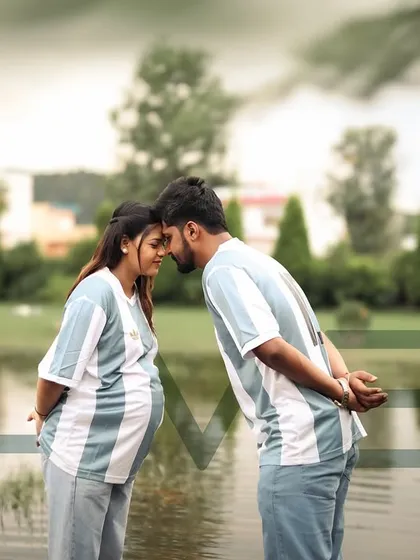 A sweet and sporty themed shot for football fans. The couple, wearing matching jerseys, share an intimate forehead-to-forehead moment by the water, ready to welcome their new team member.