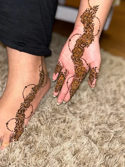 An aesthetic and minimalist design featuring a simple floral vine on the hand and foot. It’s a beautiful example of "less is more."
