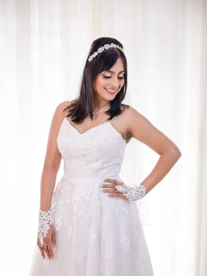 A full-length portrait of the bride in her A-line gown. The simple, clean lines of the dress are paired with a classic half-up hairstyle and natural makeup.
