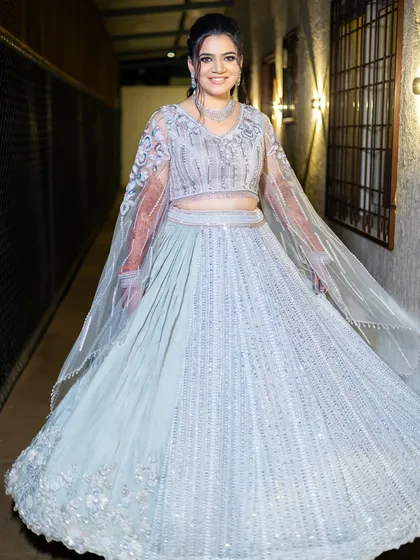 A twirling shot of the bride in her beautiful pastel blue lehenga with cape-style sleeves, perfect for a sangeet performance.