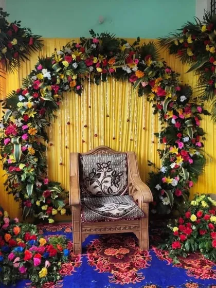 A full floral arch with a mix of colorful flowers, perfect for a vibrant celebration at home. The traditional wooden chair adds a classic touch.