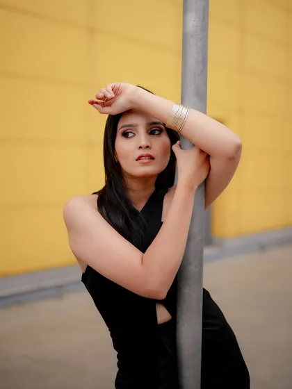 A duplicate of image 26, this portrait uses a bold yellow background and a metal pole to create a modern and graphic fashion shot.