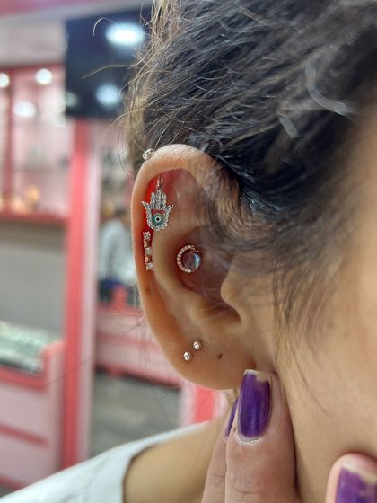 This stack features a Hamsa Hand hanging for protection, along with a delicate conch ring and multiple lobe studs.