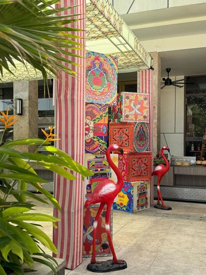 Quirky and colorful decor elements, like these stacked patterned boxes and flamingo statues, welcomed guests to the Holi party.