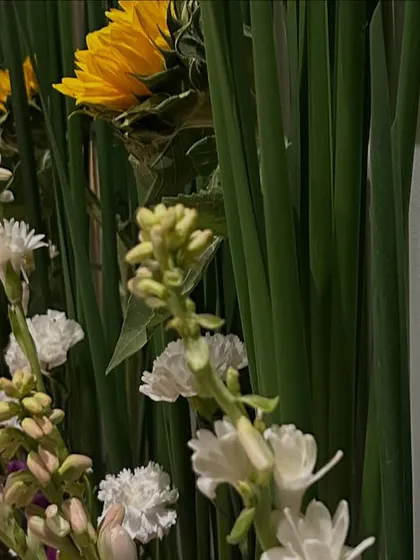 A close-up of a fresh floral wall I created. I love using a mix of textures and colors, like these sunflowers against tall green leaves and delicate white flowers, to create a natural and vibrant look.