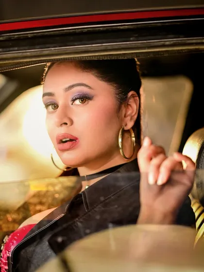 Another in-car portrait, this time with a more direct and engaging expression. The warm light highlights her makeup and confident gaze.