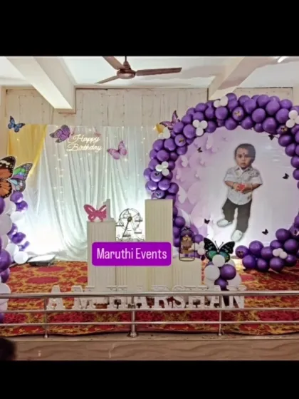 A personalized butterfly theme featuring a photo of the birthday boy inside the circular backdrop. The purple and white balloon decor adds an elegant touch.