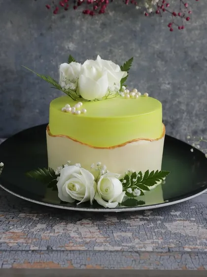 This elegant fault line cake features a refreshing lime green glaze and is decorated with beautiful fresh white roses, making it a perfect choice for anniversaries, engagements, or sophisticated parties.