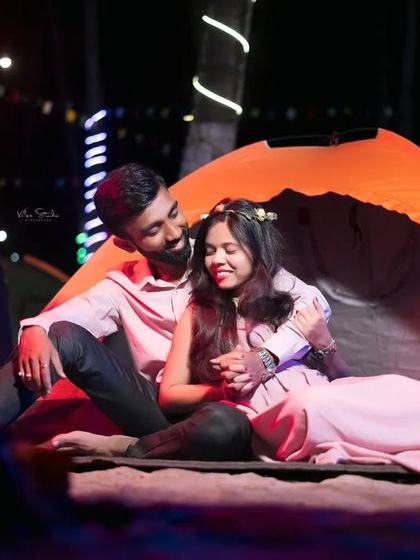 A cozy and intimate moment inside a tent during a camping-themed night shoot. The bonfire and fairy lights create a magical and romantic atmosphere.