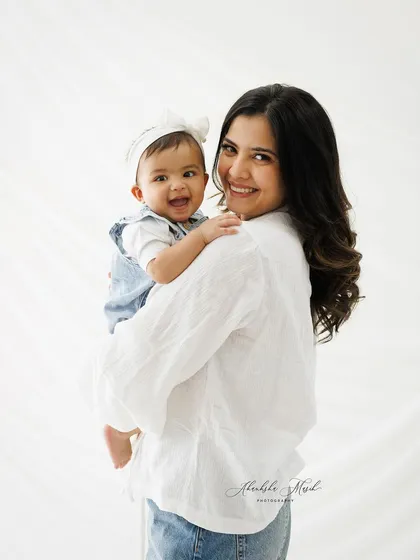 This image captures the baby looking at the camera, creating a lovely connection with the viewer, while still feeling the mother's loving presence.