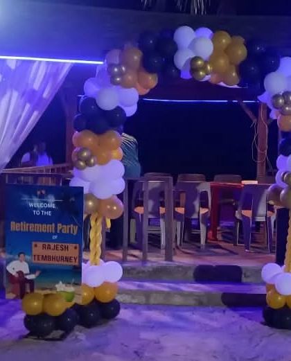 A fun, rock-and-roll themed entrance for a retirement party at a beachside location. The setup includes a balloon arch and musician silhouette cutouts.