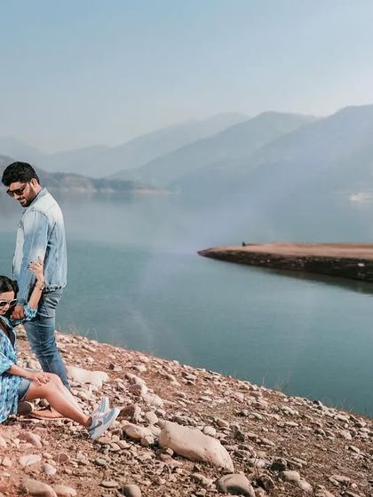 A quiet moment for the couple by the lakeside. The stunning view and their relaxed posture create a peaceful and intimate portrait.