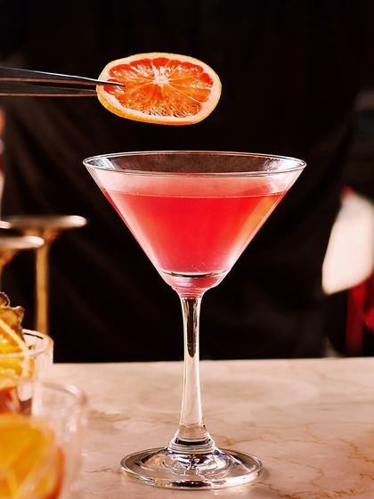 Indulge in elegance. Our bartender carefully garnishes a classic cosmopolitan, ensuring every drink served is a picture of perfection.