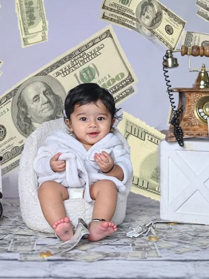 A fun 'Boss Baby' or 'Money' theme for a toddler. This setup with a vintage phone and falling dollars is great for capturing a playful and confident personality.