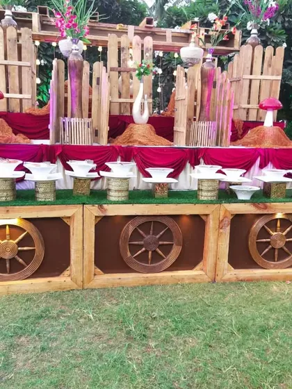 A rustic, woodland-themed buffet counter setup for an outdoor event, featuring wooden wheels and mushroom-shaped decor.