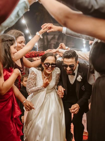 Pure joy on their faces. Ryan and Ela, sporting cool shades, enjoy a fun-filled entry surrounded by their friends and family, making for a truly memorable and personal moment.