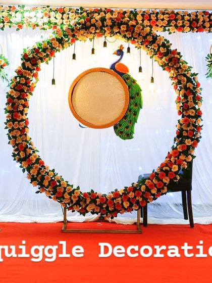 A beautiful floral ring backdrop for a naming ceremony. The setup includes a peacock prop and traditional lighting, creating a perfect setting for the special occasion.