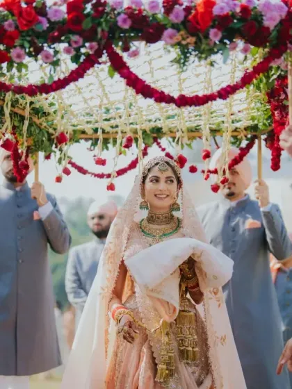 The bride makes her graceful entrance under a traditional phoolon ki chaadar. I work to honor these timeless Sikh and Hindu wedding customs, ensuring they are presented with elegance and personal significance.
