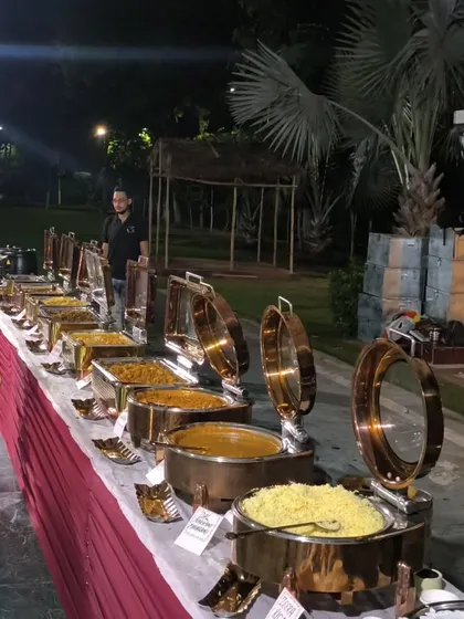 A full dinner spread ready for an evening event in a garden setting. The buffet includes a variety of main courses, rice, and breads, all kept warm in our high-quality copper chafing dishes.
