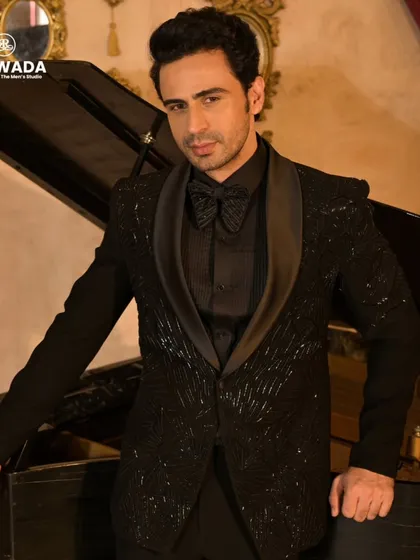 Posed by a piano, this shot emphasizes the classic, timeless appeal of the black sequined tuxedo. It's an outfit for a modern virtuoso.