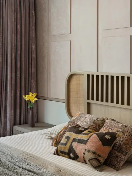 Designed for the elderly couple, this bedroom has a Zen approach with a calm, monochrome appearance. The headboard features a mix of cane and wood, set against a wall with a geometric stucco texture.