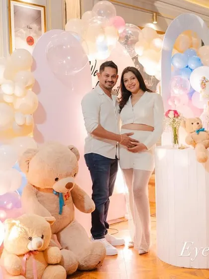 A beautiful portrait of the parents-to-be in front of the "We Can Barely Wait" teddy bear themed decor. The soft lighting and blend of pink and blue balloons create a dreamy setting for capturing these precious memories.